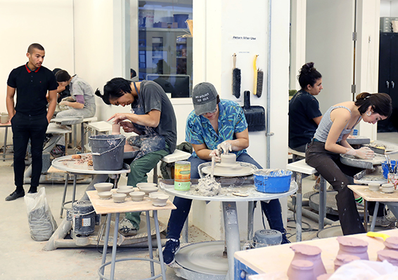 Students in a ceramics class work on pottery wheels.