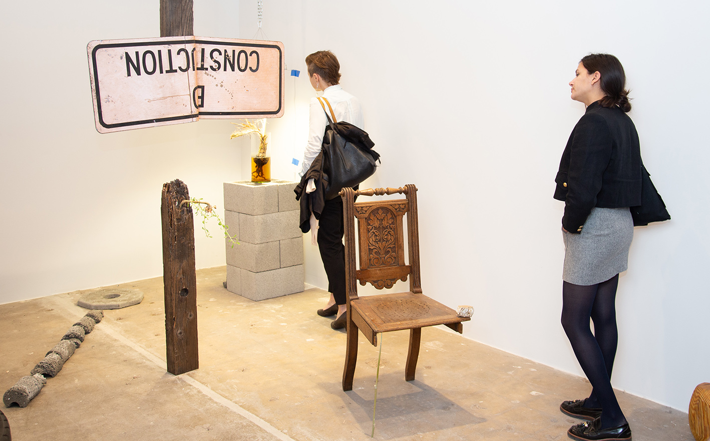 Two people walk through sculptures installed in a studio
