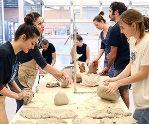 Students work with clay at a wedging table