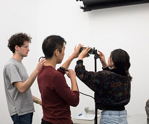 Three students adjust a studio light