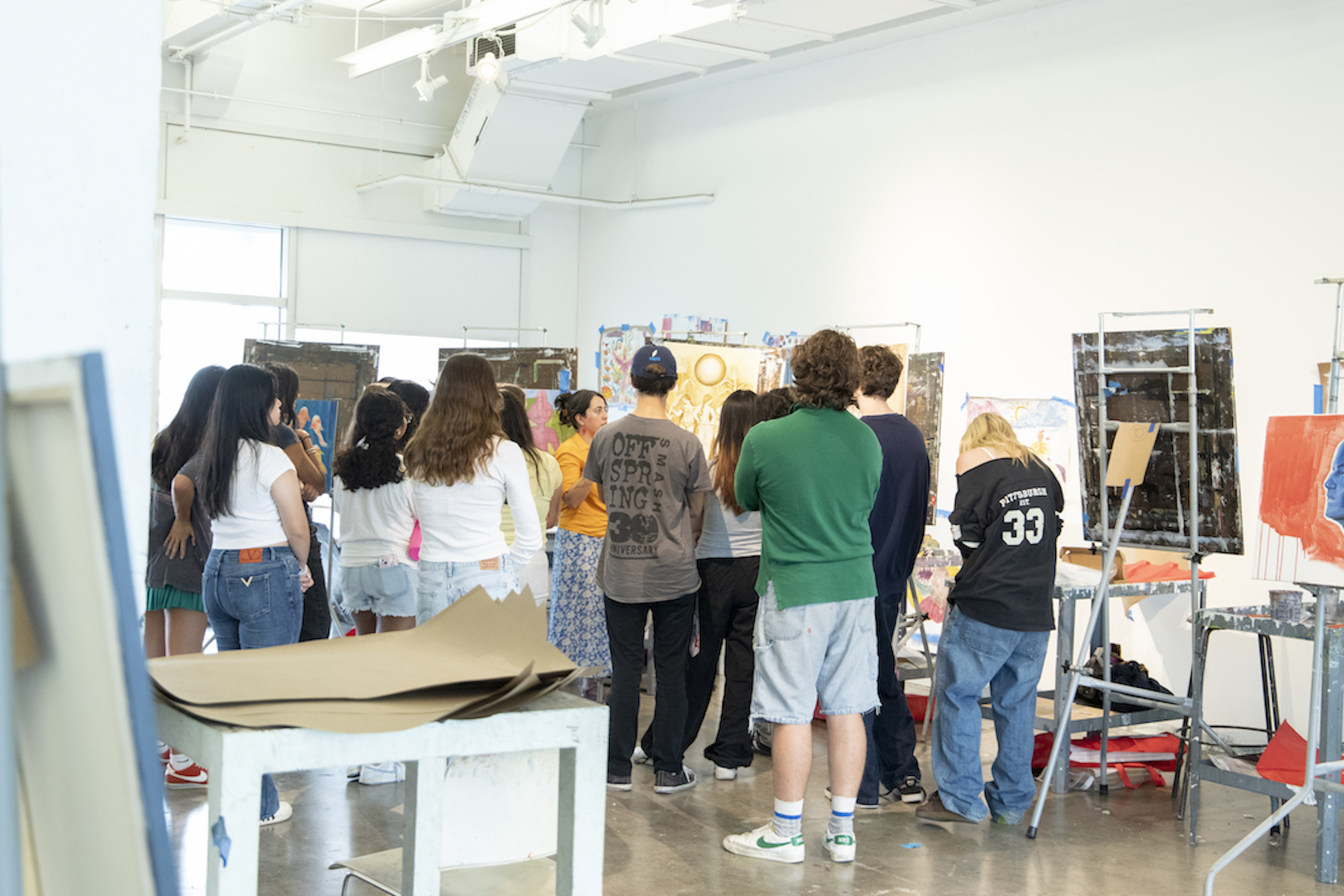 A group of students standing and listening to their professor.